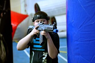 Мальчик в черной футболке "Синяя команда" с оружием LASERWAR.